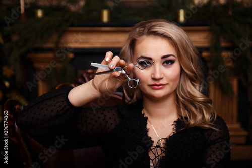 girl in a black dress with scissors in her hands. preparation for the new year, christmas. hairstyle. tidy yourself up. preparation for the holidays