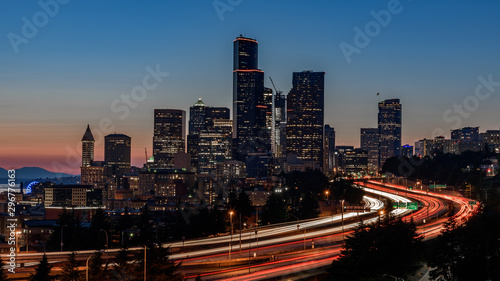 Seattle skyline  at sunset. The cars along the highway are creating light trails  due to a slow shutter speed