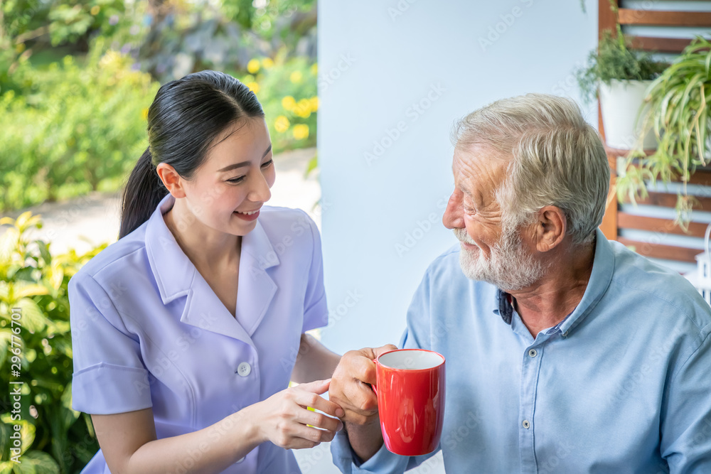 Nurse assist elderly senior man to drink coffee with mug in hand at nursing home Nurse assist elderly senior man to drink coffee with mug in hand at nursing home
