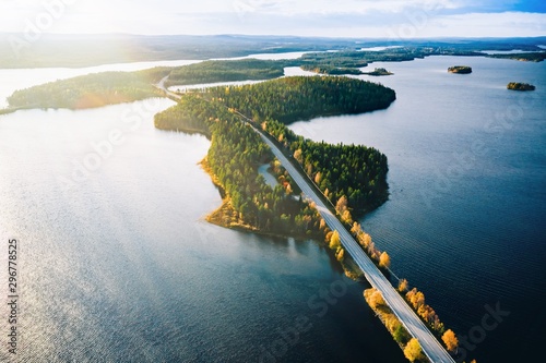 Aerial view of bridge across blue lakes with sun light in colorful autumn forest in Finland. photo