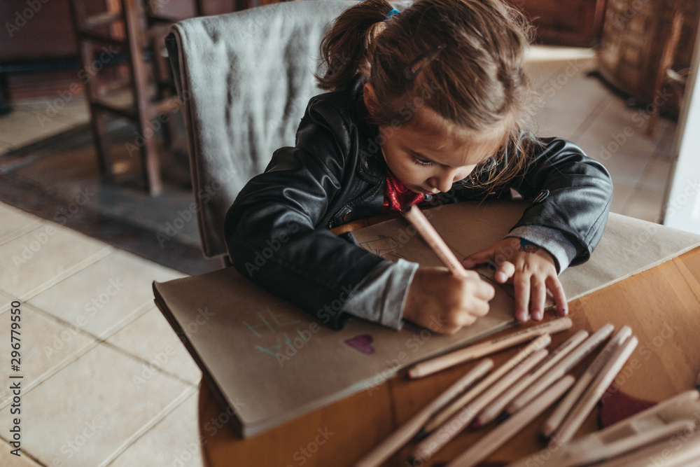 Adorable preschool girl drawing with wooden pencils in a cozy cafe. Cute daughter smiling and drawing colorful shapes for kindergarten homework