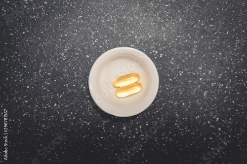 gelatin capsules with fish oil in a pill box. omega 3 pills, top view.