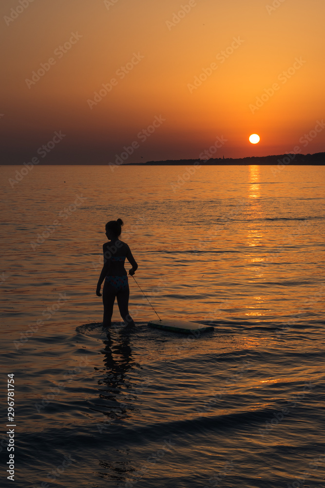 la silhouette d'une femme devant un coucher de soleil à lamer. Une surfeuse au coucher de soleil.