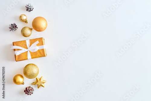 Flat lay christmas border with gold christmas balls and gift box on a white background