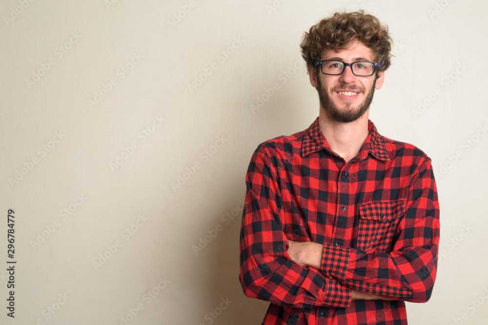 Happy young bearded hipster man smiling with arms crossed Happy young bearded hipster man smiling with arms crossed