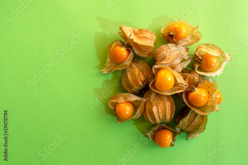 Pile of golden berries isolated on green background with copy space. Physalis fruit. Golden berries. 