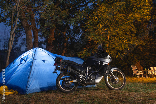 night camp in the forest, trailer house and touristic tent. adventure motorcycle tour, seasonal vacation, light from the tent. space for text.