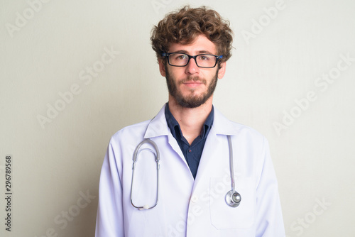 Face of young bearded man doctor with curly hair wearing eyeglasses