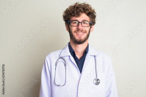 Face of happy young bearded man doctor with eyeglasses smiling