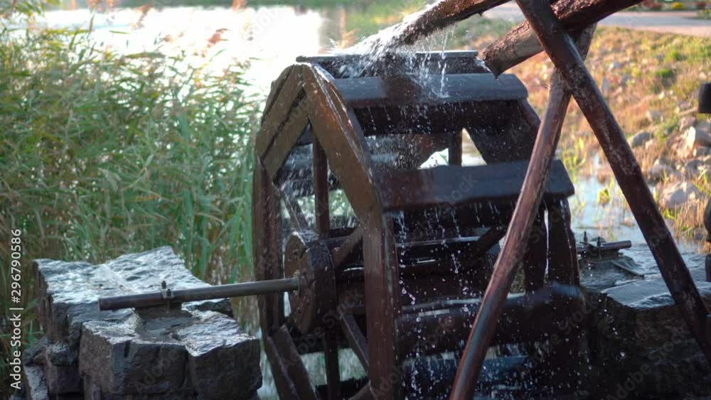 The pressure of water rotates an old water mill. Spray flying in different directions The pressure of water rotates an old water mill. Spray flying in different directions
