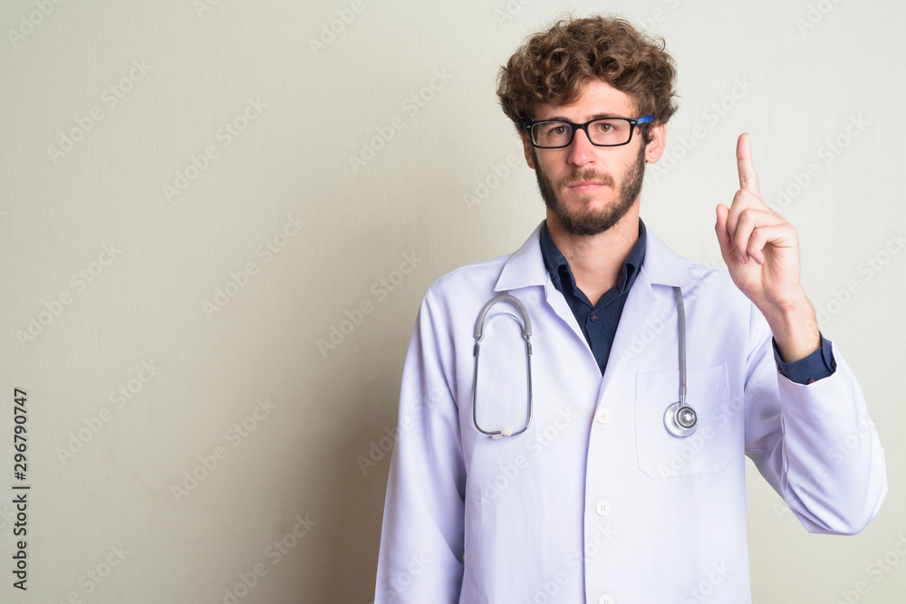 Young bearded man doctor with eyeglasses pointing up