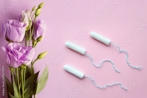 Medical female tampons and flowers on pink background. White tampon for women. Menstruation, means of protection. © Kristina