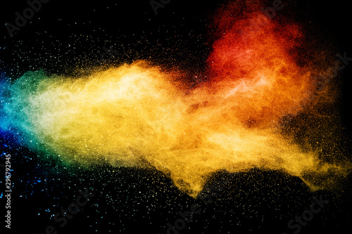Yellow red blue powder explosion cloud on black background. Freeze motion of color dust particles splashing.