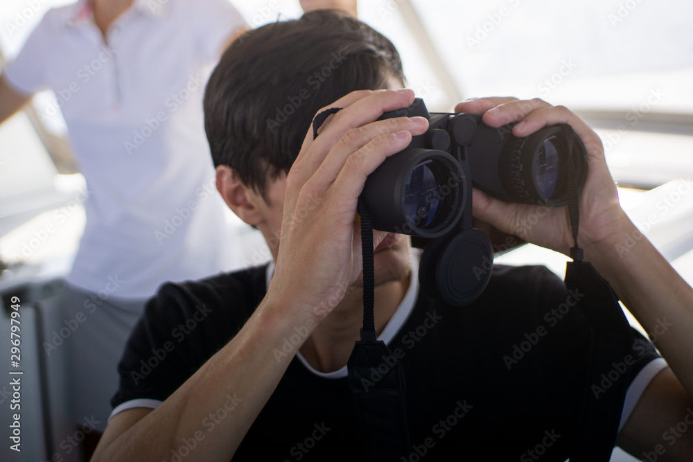 beautiful young man at the yacht vacation on the Mediterranean Sea looking through binoculars