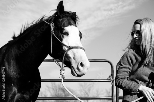 Woman with horse in halter after training, animal care concept close up in black and white.