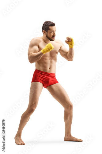 Strong young man in red shorts exercising kickboxing