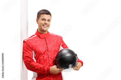 Car racer holding a helmet and leaning against a wall