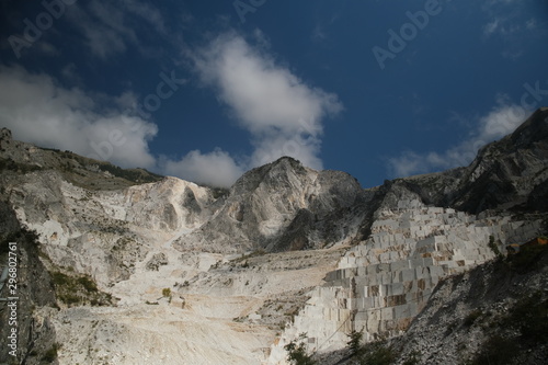 Panorama of a white Carrara marble quarry in Tuscany. Mountains of the Apuan Alps, blue sky and cloud.