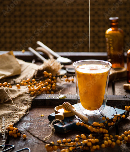 hot drink with sea buckthorn berries and honey in tall glass