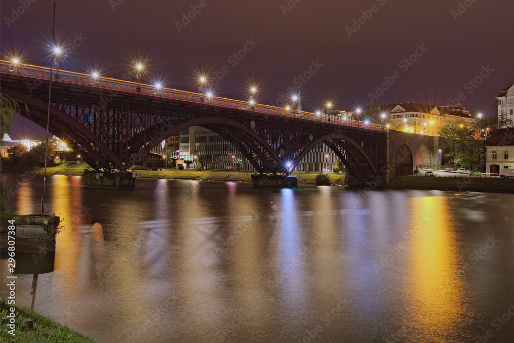Night landscape view of illuminated Old Bridge (also named the State) over Drava River. Popular travel destination in Maribor, Slovenia
