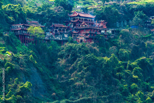 The ancient Taoist monastery in China on the side of the mountain among the forest and bushes. Chinese city of Chongqing.