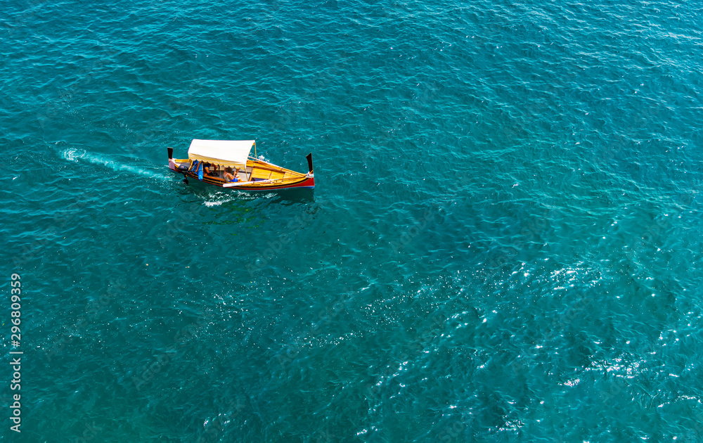 Aerial top view of luzzu - traditional wooden colorful fishing boat in Valletta Grand Harbor, Malta, with turquoise Mediterranean sea. Aerial top view of luzzu - traditional wooden colorful fishing boat in Valletta Grand Harbor, Malta, with turquoise Mediterranean sea.