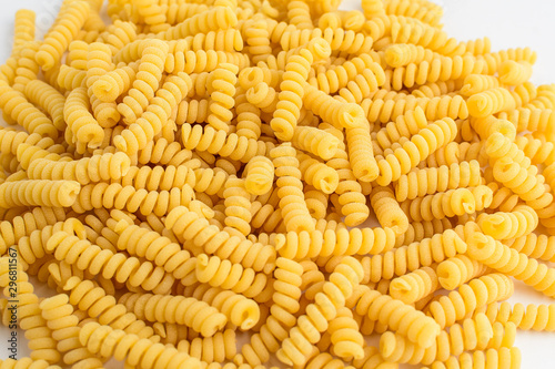 Close up of dried fusilli Italian pasta in a round shape ready to be cooked, isolated on white table, with view from above 