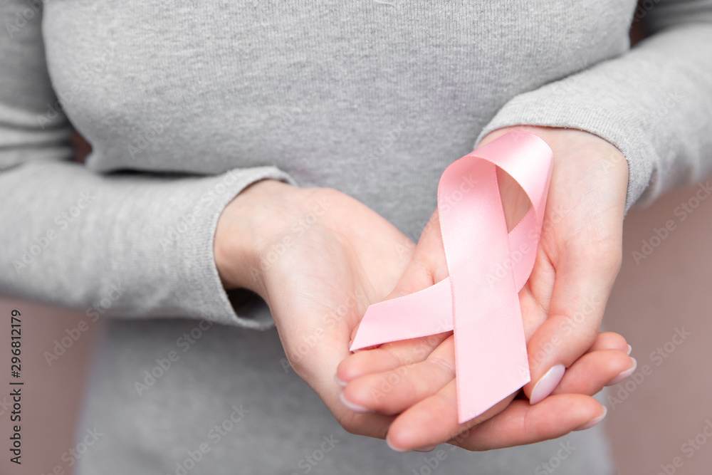 Girl hands holding pink breast cancer awareness ribbon on gray background. Concept healthcare and medicine beauty Girl hands holding pink breast cancer awareness ribbon on gray background. Concept healthcare and medicine beauty