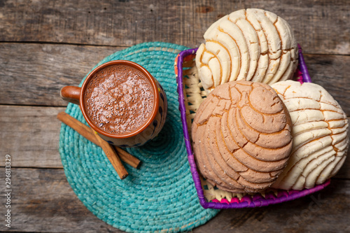 Mexican hot chocolate with sweet conchas bread on wooden background