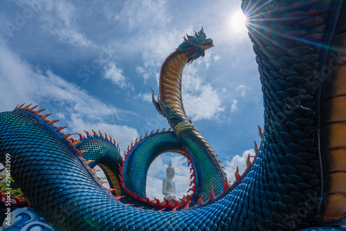 Canvas Print Giant Thai Naga Statue with blue sky clouds in the Phu Manorom Temple, Statue of Naka Buddha and White large Buddha statue at Mukdahan Province, Thailand