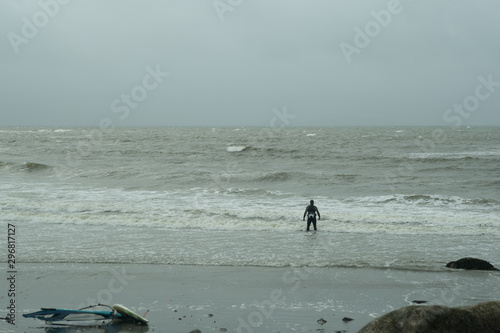 Surfer approaching to the wavy water during bad stormy irish weather. Windsurfing and board beside on the beach. Ring of Kerry. Ireland