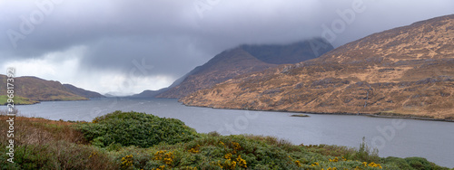 Panoramic view on lake in Irish mountains during stormy weather, green bush. Ring of Kerry, Ireland