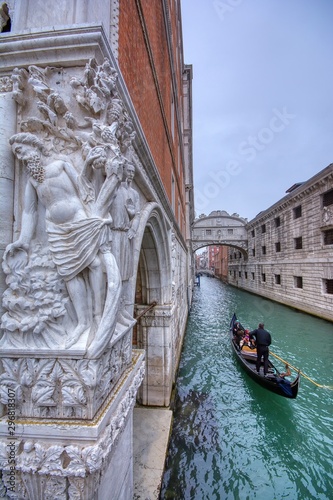 Gondola with tourists sails on old canal under medieval Bridge of Sighs, Venice, Italy. © StockPhotoAstur