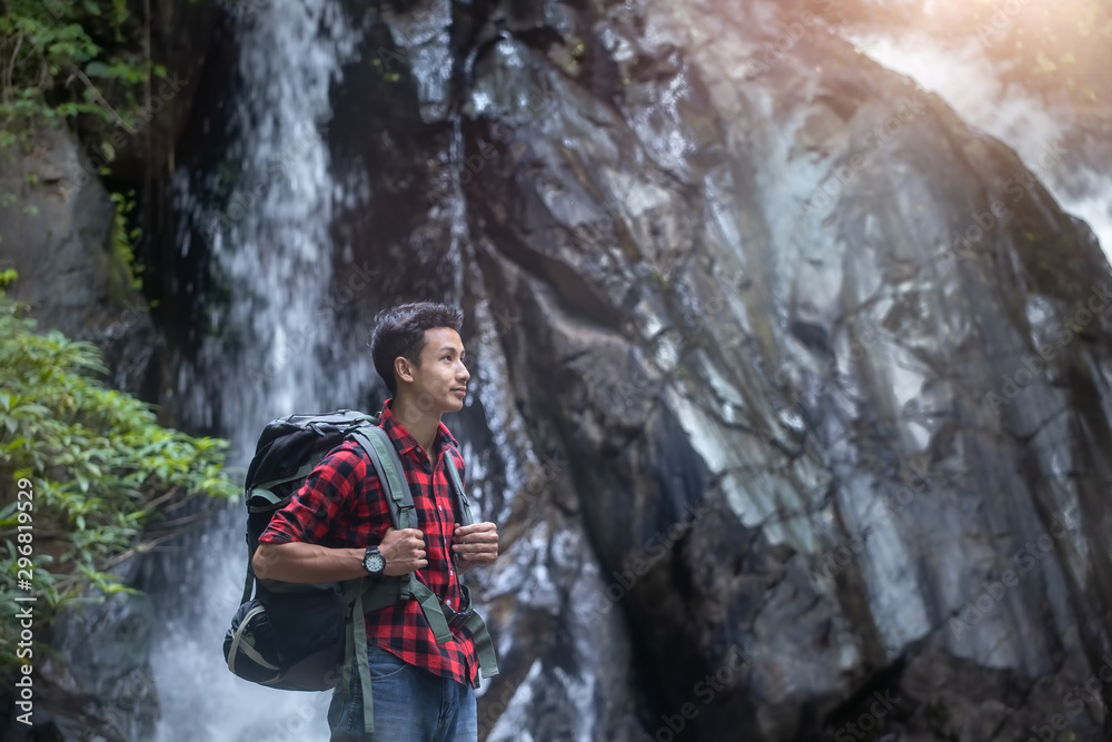 Young hiker standing in front of the waterfall with backpack. travel concept.