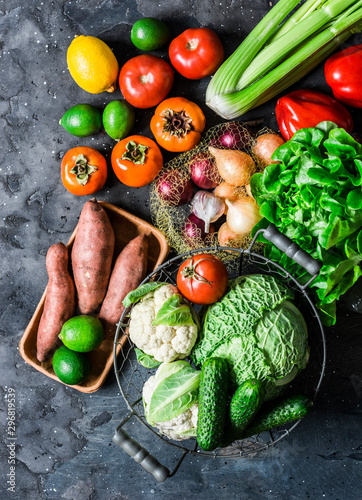 Fototapeta Naklejka Na Ścianę i Meble -  Fresh organic vegetables, fruits on a dark background, top view. Healthy diet food concept. Sweet potato, savoy cabbage, sweet peppers, celery, cucumbers, tomatoes, persimmon - vegetarian food