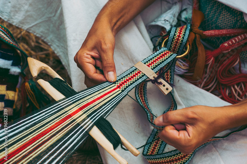 Woman dressed in colorful traditional native Serbian closing knitting a carpet with national pattern