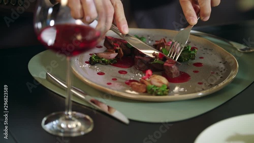 Male hands cutting meat steak at restaurant. Business man dining in restaurant