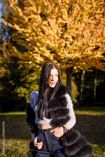 beautiful girl with long hair smiles nicely in the autumn park, fur coat, fur