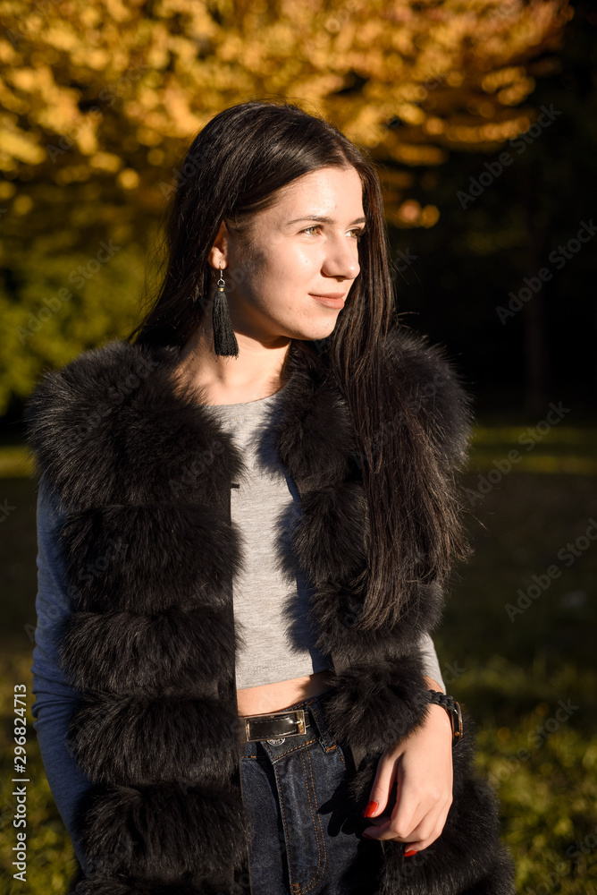 beautiful girl with long hair smiles nicely in the autumn park, fur coat, fur