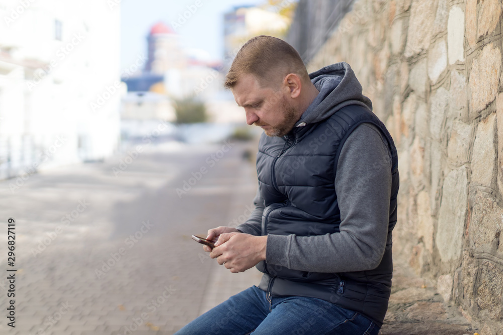Serious middle-aged man with a smartphone, he writes a message or comments on social networks. Serious middle-aged man with a smartphone, he writes a message or comments on social networks.