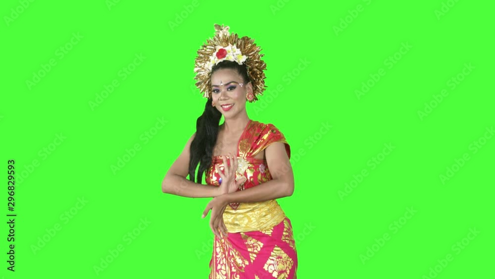 Attractive balinese dancer smiling at the camera while dancing in the studio. Shot in 4k resolution with green screen background Attractive balinese dancer smiling at the camera while dancing in the studio. Shot in 4k resolution with green screen background