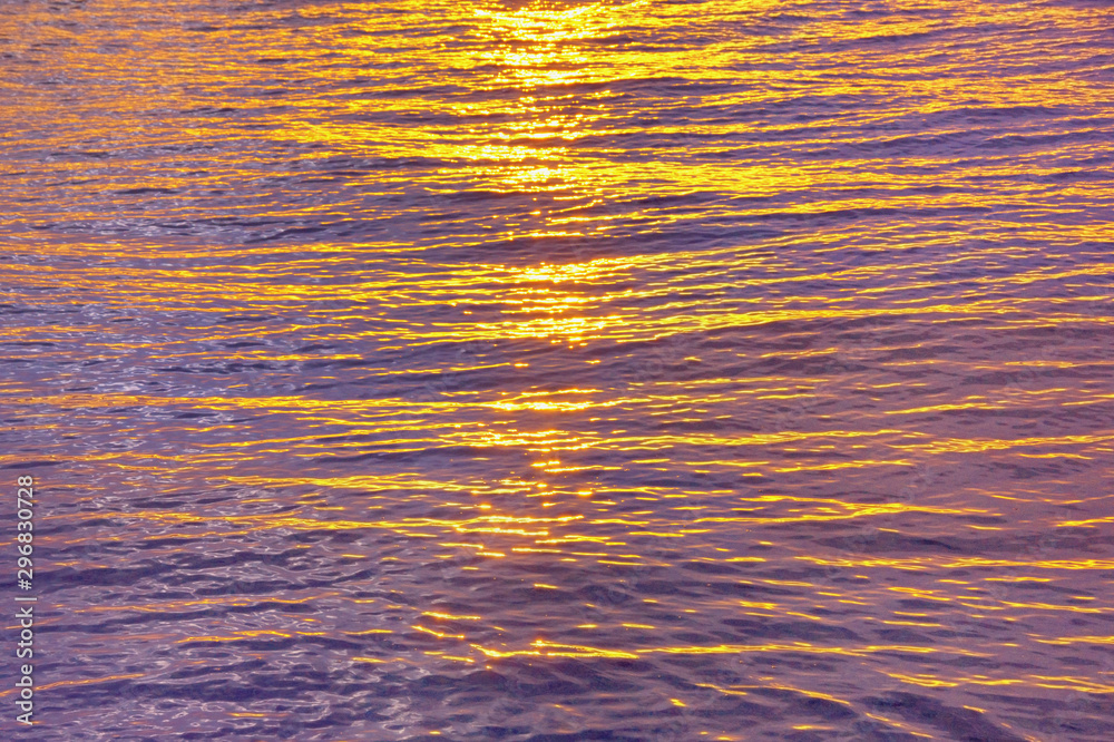 Beautiful yellow-purple background. Natural texture of sea water, illuminated by setting sun. Montenegro, Adriatic Sea
