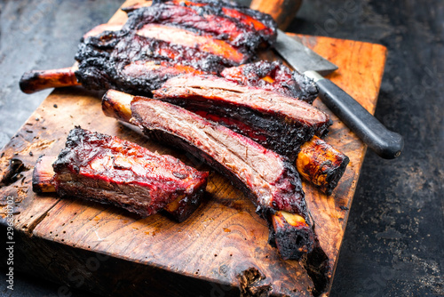 Barbecue burnt chuck beef ribs marinated with hot chili sauce sliced as closeup on an old rustic wooden cutting board