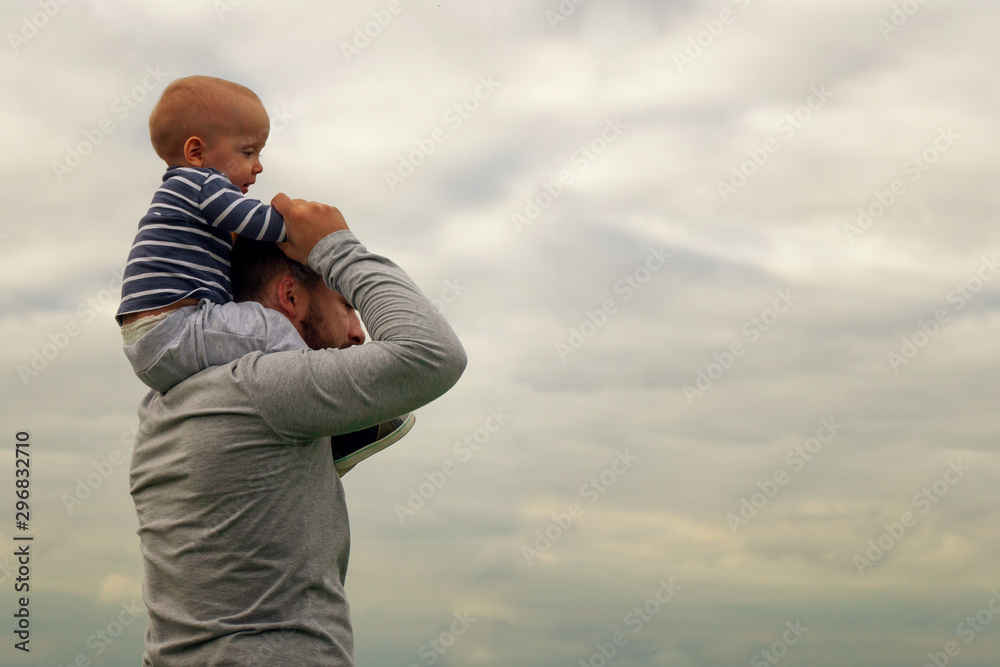A child on his father’s neck. Walk near the water. Baby and dad against the sky. A child on his father’s neck. Walk near the water. Baby and dad against the sky.