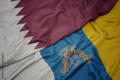 waving colorful flag of canary islands and national flag of qatar.