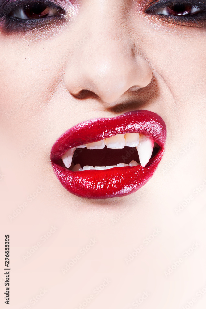 Obraz premium Sexy vampire. Women's lips with red lipstick. Screaming mouth with vampire fangs,