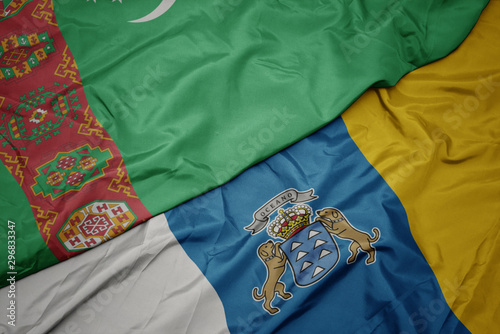 waving colorful flag of canary islands and national flag of turkmenistan.