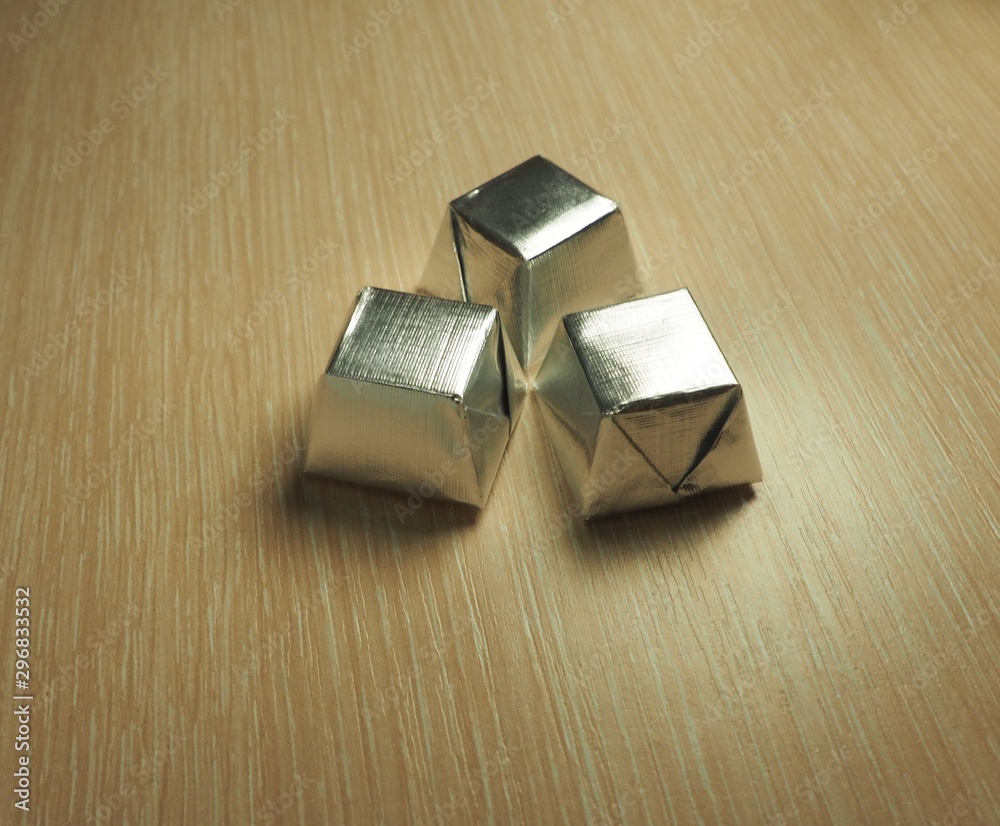 Photo of  sweets in a silver wrapper on a light wood background