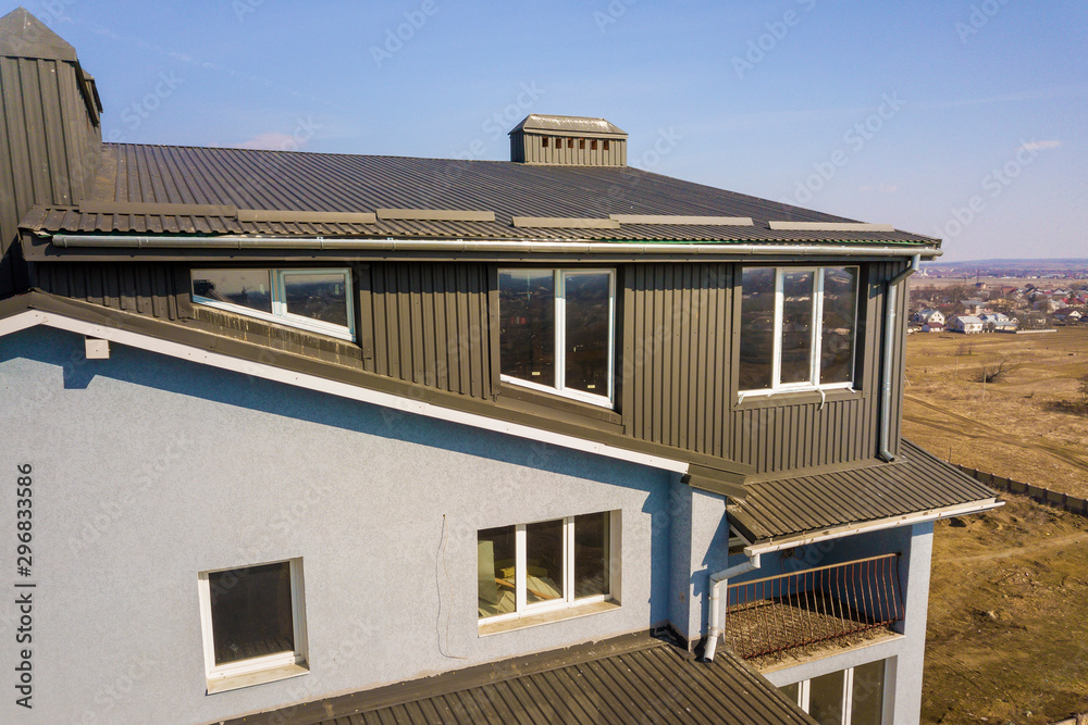 Aerial view of attic annex room exterior with plastic windows, roof and walls covered with brown metal decorative siding planks, new gutter system on top of apartment building. Aerial view of attic annex room exterior with plastic windows, roof and walls covered with brown metal decorative siding planks, new gutter system on top of apartment building.