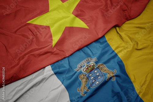 waving colorful flag of canary islands and national flag of vietnam.